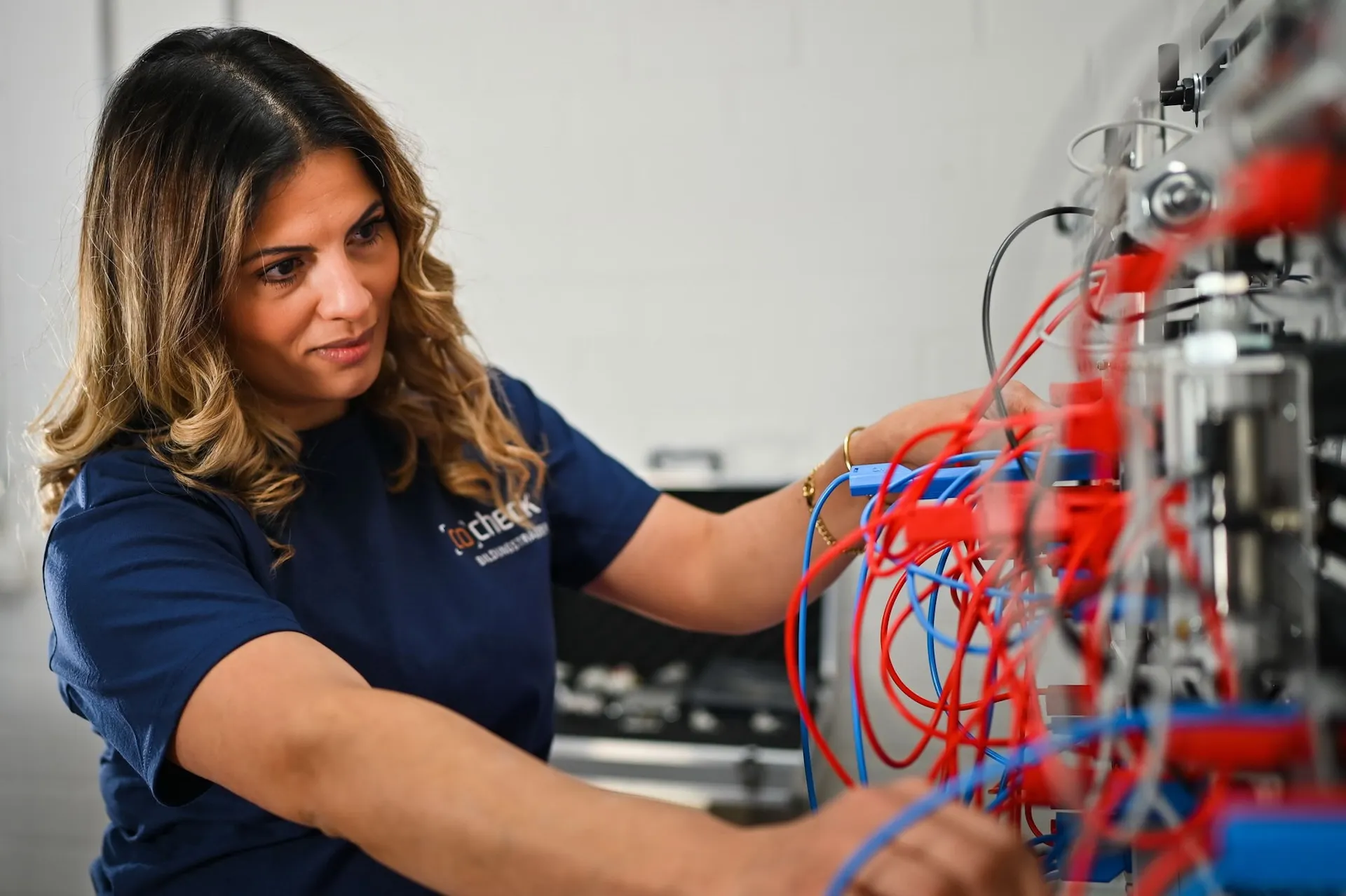 Mitarbeiterin verkabelt Teststation – Unternehmensfotografie aus dem Bereich Elektrotechnik in Nürnberg.