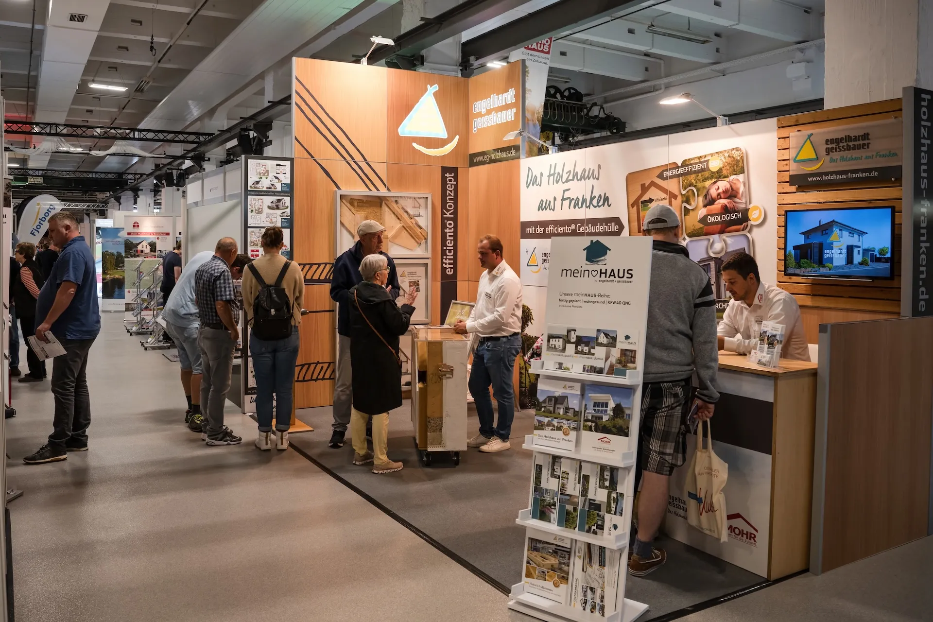 Messestand von Holzhaus Franken – Architektur und Materialien im Bild betont.