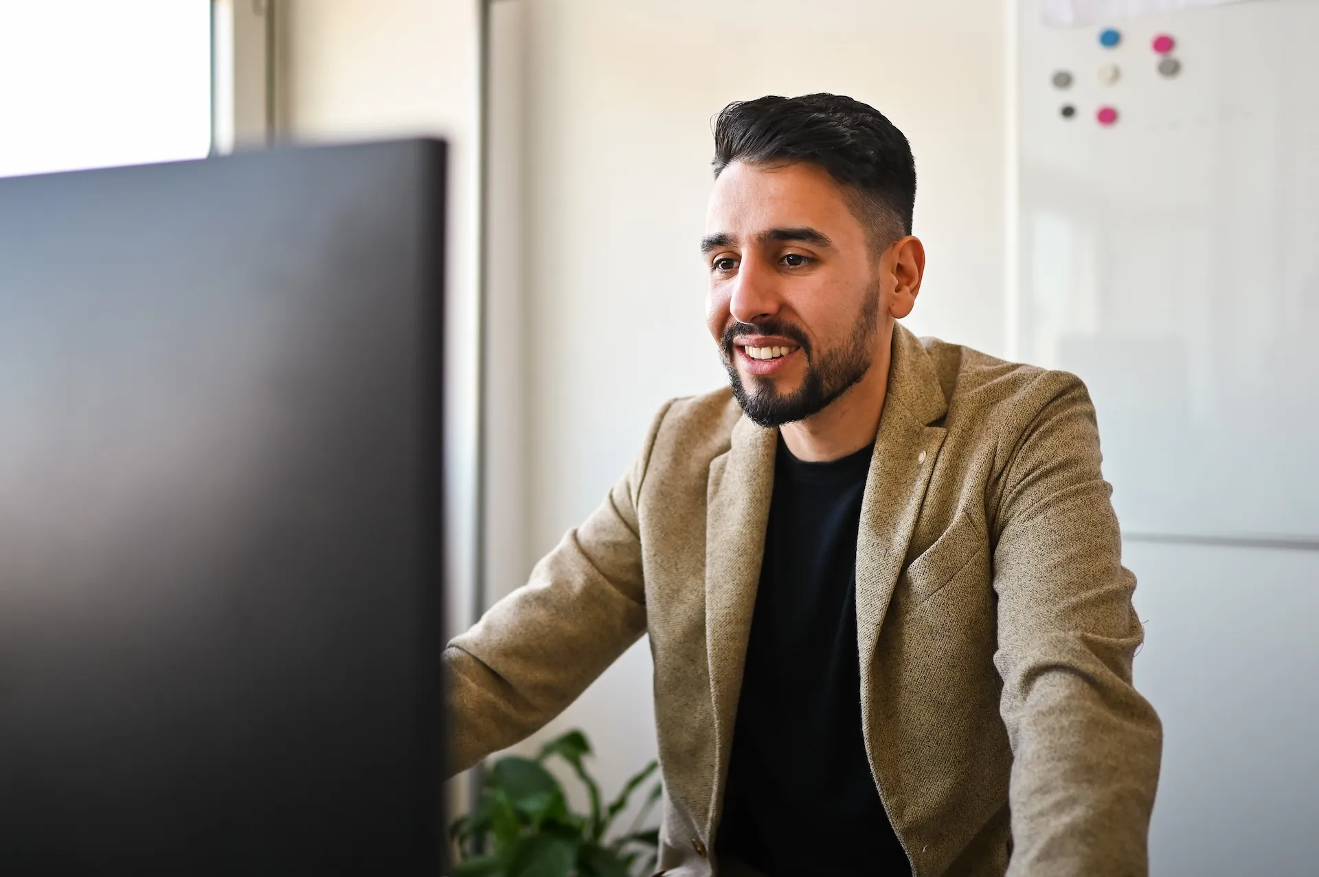 Mitarbeiter mit Sakko vor Bildschirm – Fokus und Kompetenz