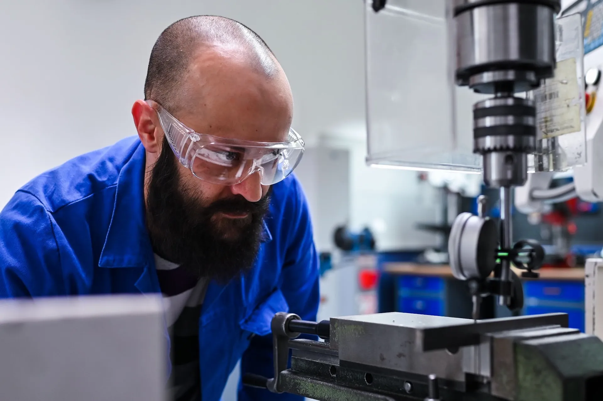 Mitarbeiter bedient eine Bohrmaschine mit Schutzbrille – authentische Industriefotografie in Nürnberg.