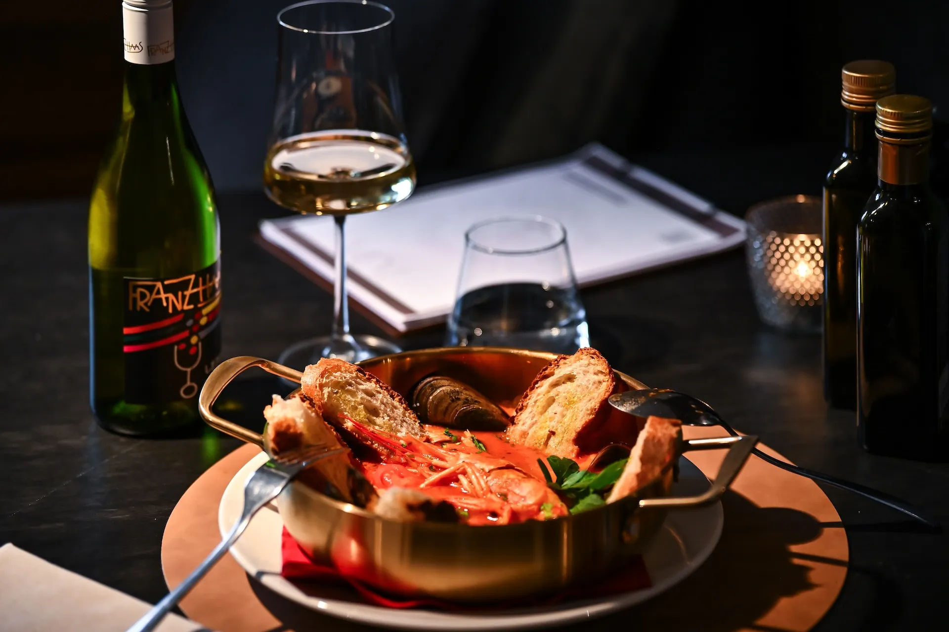 Gedeckter Tisch mit Pfanne mit Meeresfrüchten und Weißwein