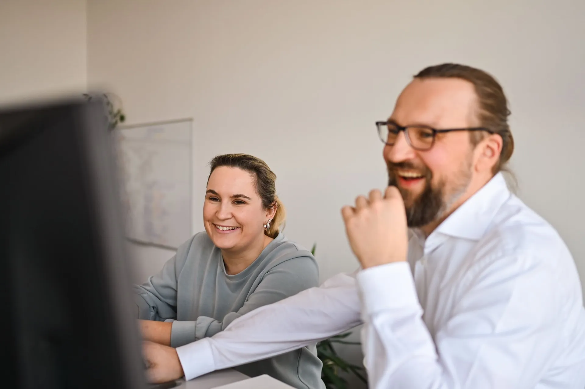 Lächelnde Kollegen bei der Zusammenarbeit im Büro – authentische Teamdarstellung durch Unternehmensfotografie in Nürnberg.
