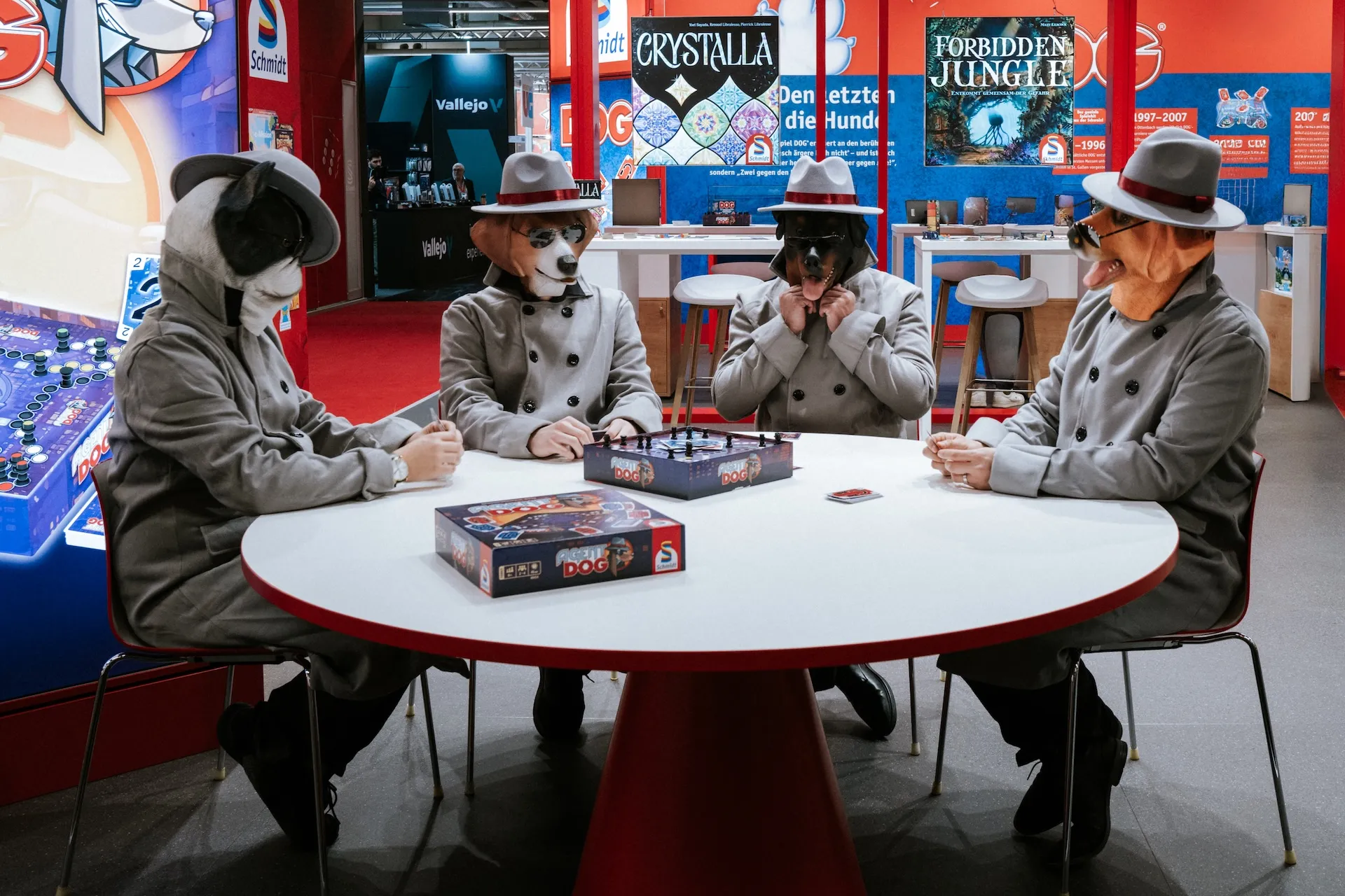 Kreative Szene auf dem Messestand – vier Männer mit Hundemasken beim Brettspiel.